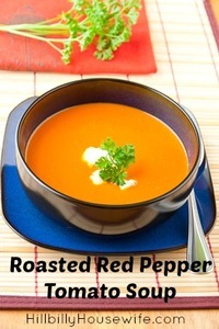 Bowl of tomato and  red pepper and basil soup garnished with cream and parsley