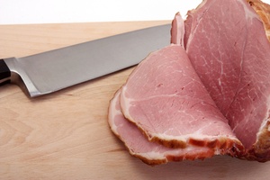 delicious smoked and sliced ham on a board with knife