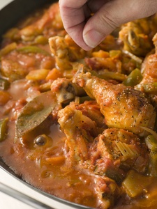 Creole Seasoning being sprinkled into a chicken dish