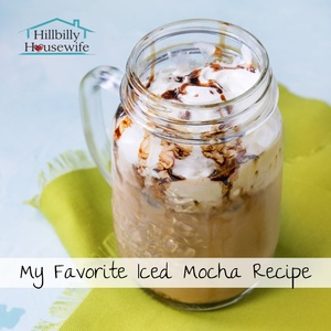 A mason jar filled with iced mocha and topped with whipped cream and chocolate syrup. 