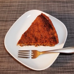 A slice of homemade pear cake made from fresh pears on a white plate with fork.