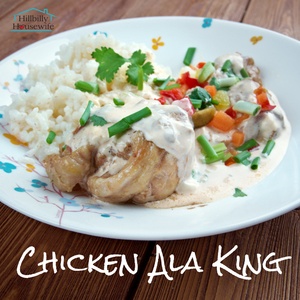 A plate of chicken ala king over a puff pastry with a side of vegetables and rice